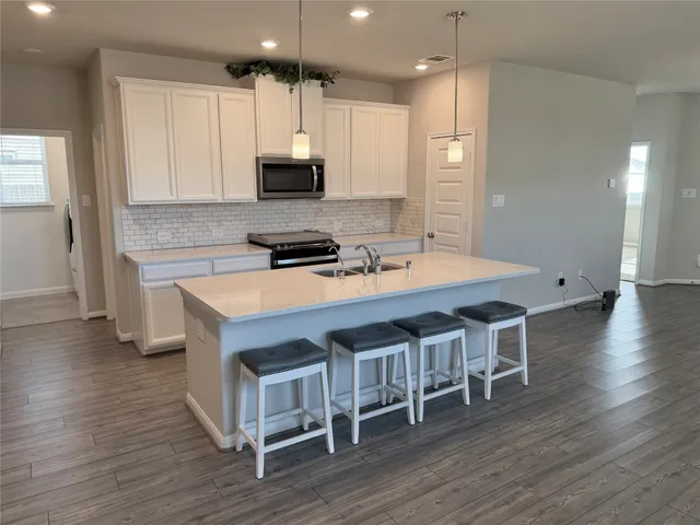 a kitchen with stainless steel appliances a stove a sink dishwasher and a refrigerator with wooden floor