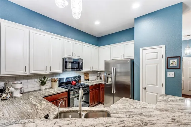 a kitchen with stainless steel appliances granite countertop a refrigerator stove top oven a sink and dishwasher