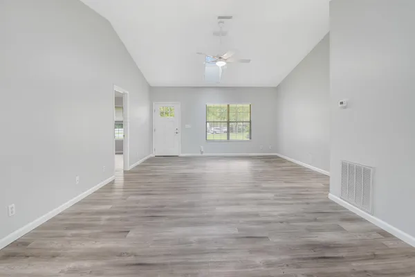 an empty room with wooden floor and windows