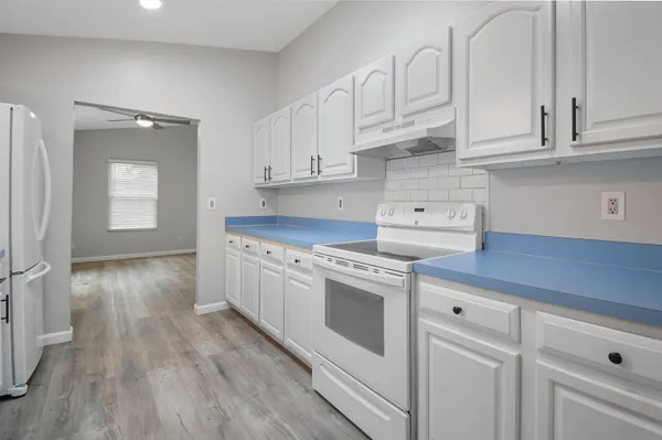 a kitchen with granite countertop white cabinets and white appliances