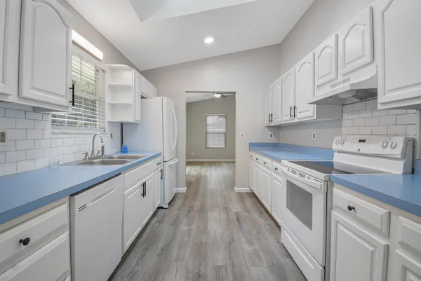 a large kitchen with granite countertop a large counter top space a sink stainless steel appliances and cabinets