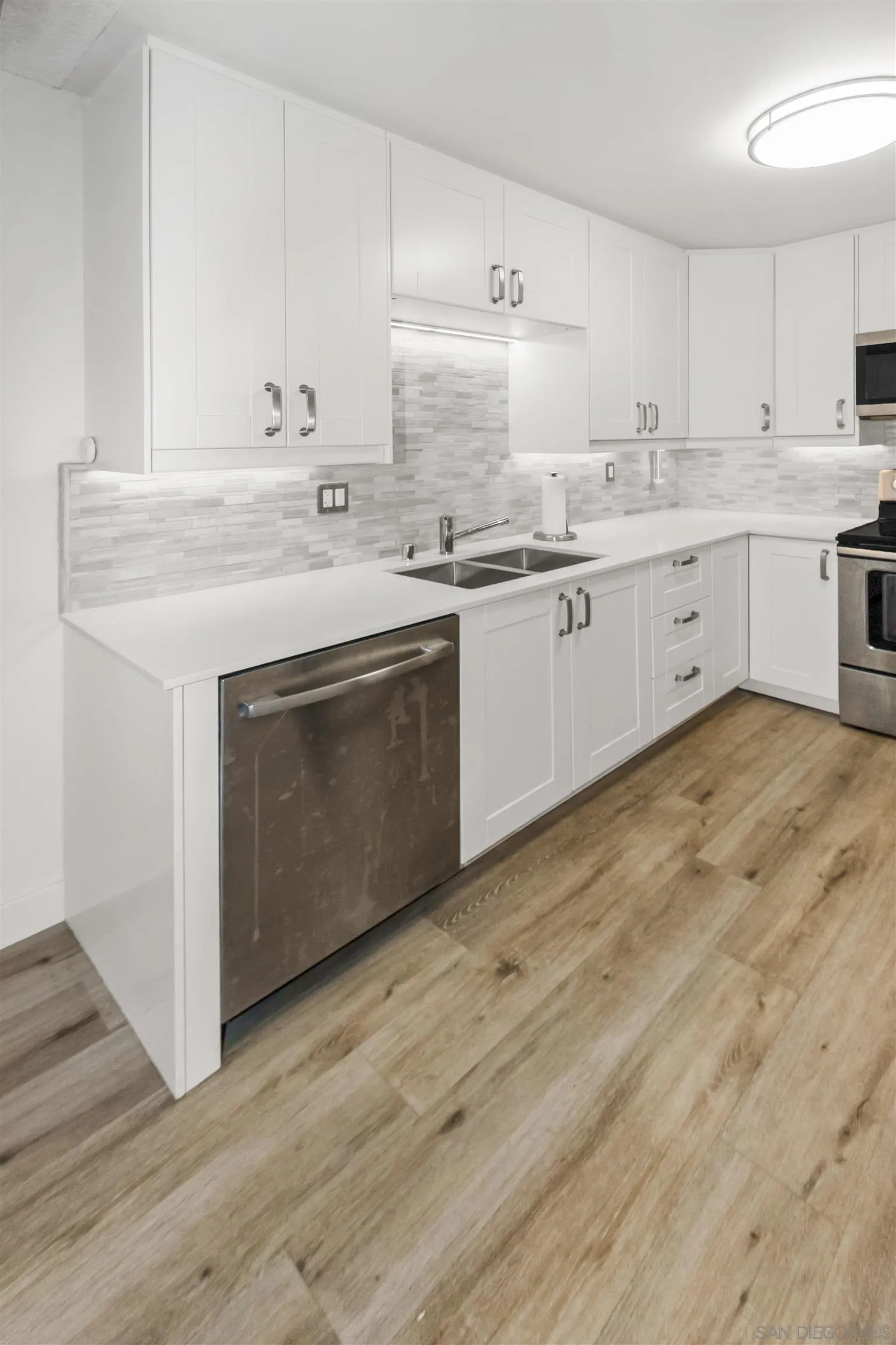 502 E Avenue Coronado, CA 92118 - Photo 8 of 18 a kitchen with stainless steel appliances granite countertop a sink and cabinets with wooden floor