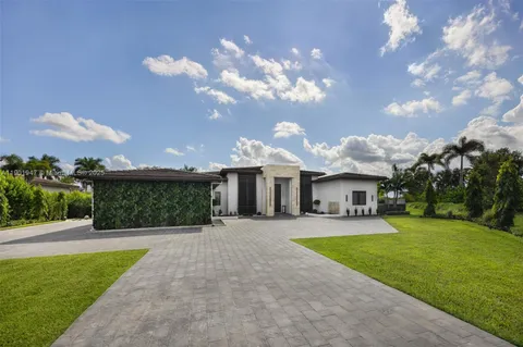 a view of a house with a big yard plants and large trees