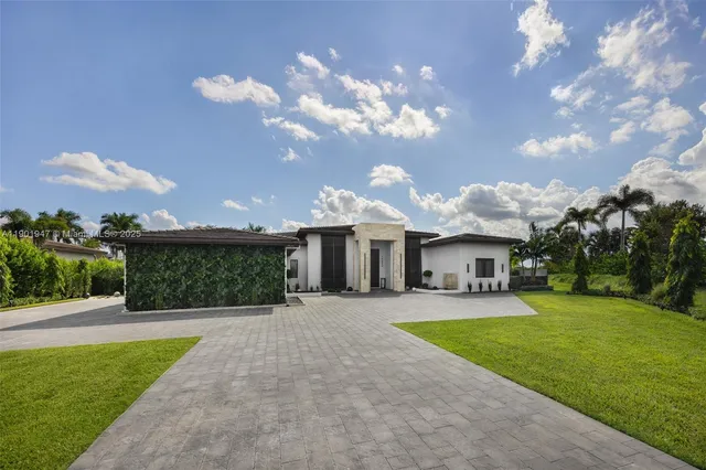 a view of a house with a big yard plants and large trees