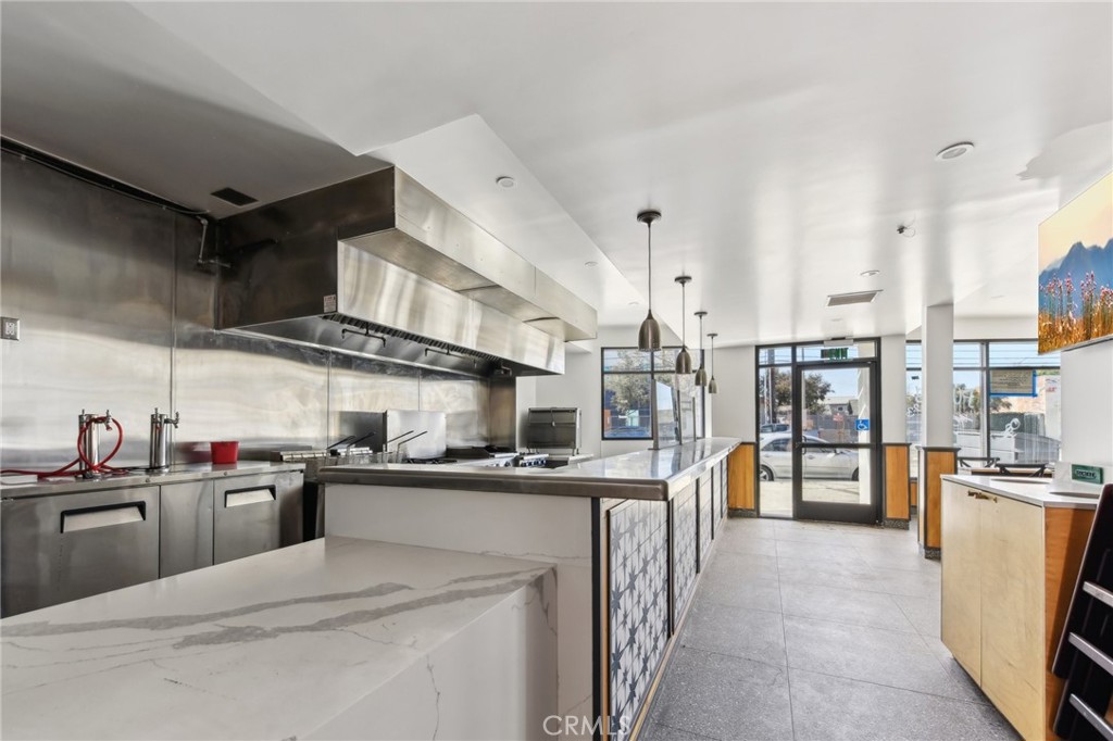 9320 Long Beach Boulevard South Gate, CA 90280 - Photo 22 of 30 a kitchen with stainless steel appliances a sink a stove top oven a chimney cabinets and a dining table
