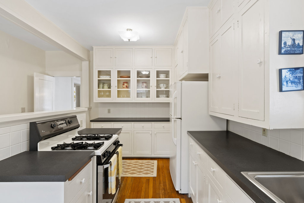 1609 Wethersfield Road Austin, TX 78703 - Photo 12 of 38 Kitchen with dark countertops, range with gas stovetop, and white cabinetry