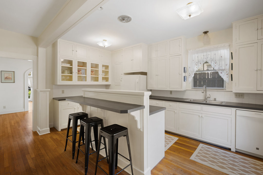 1609 Wethersfield Road Austin, TX 78703 - Photo 13 of 38 Kitchen with a kitchen breakfast bar, dark countertops, white appliances, glass insert cabinets, and light wood-style flooring