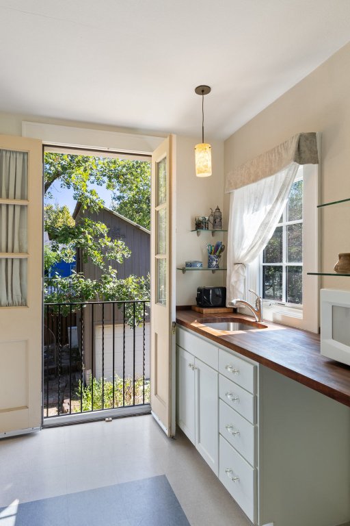 1609 Wethersfield Road Austin, TX 78703 - Photo 24 of 38 Kitchen with butcher block counters, light flooring, decorative light fixtures, and white cabinets