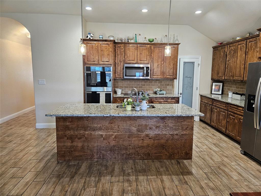 904 Avagail Avenue Springtown, TX 76082 - Photo 14 of 27 a large kitchen with stainless steel appliances granite countertop a stove and a wooden floors