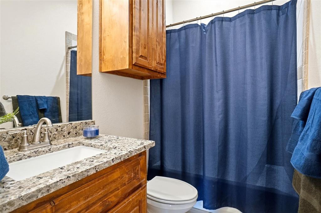 904 Avagail Avenue Springtown, TX 76082 - Photo 23 of 27 a bathroom with a granite countertop sink toilet and shower