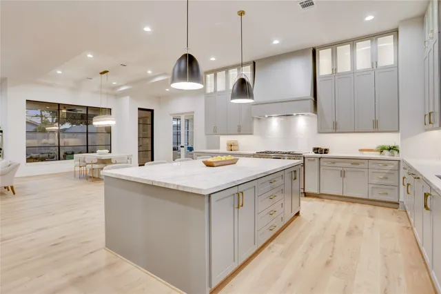 a large kitchen with stainless steel appliances kitchen island a large counter top a sink a stove and a refrigerator