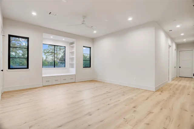 an empty room with wooden floor and windows
