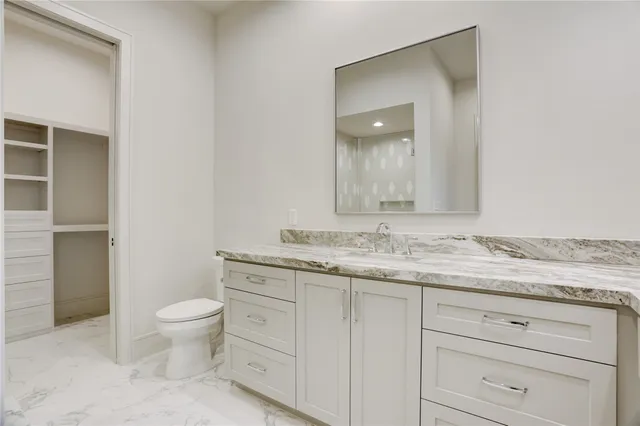 a bathroom with a granite countertop toilet and sink
