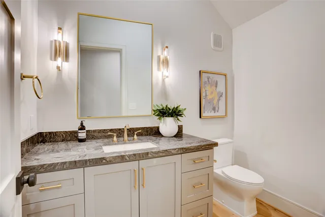 a bathroom with a granite countertop toilet sink and mirror