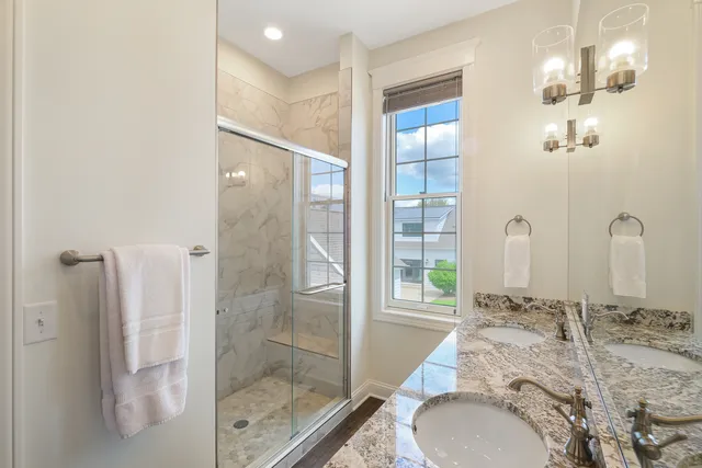 a bathroom with a granite countertop sink a mirror and a shower