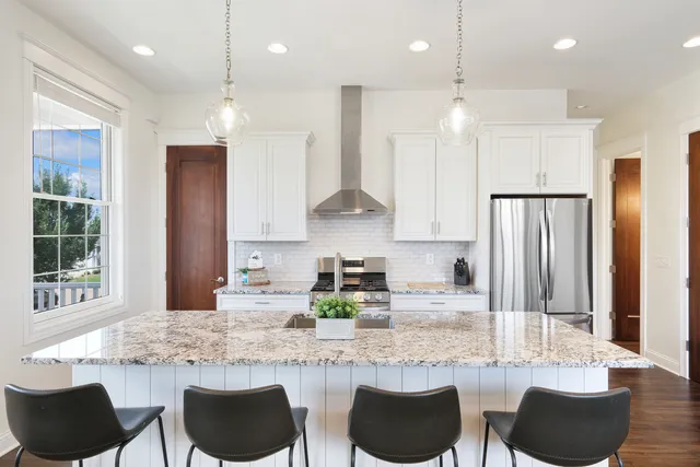 a kitchen with granite countertop kitchen island stainless steel appliances a dining table and chairs