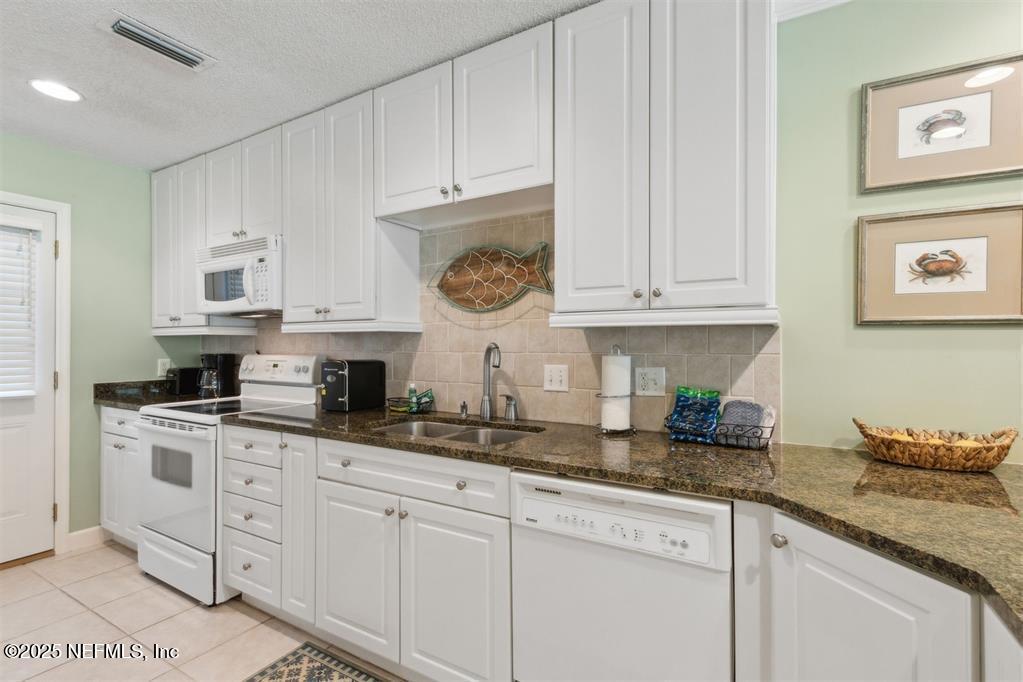 3328 Sea Marsh Road Fernandina Beach, FL 32034 - Photo 13 of 44 a kitchen with granite countertop white cabinets and white appliances