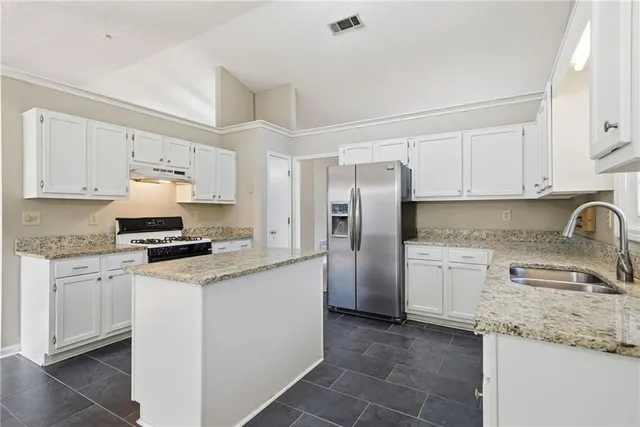 a kitchen with granite countertop a sink stove and refrigerator