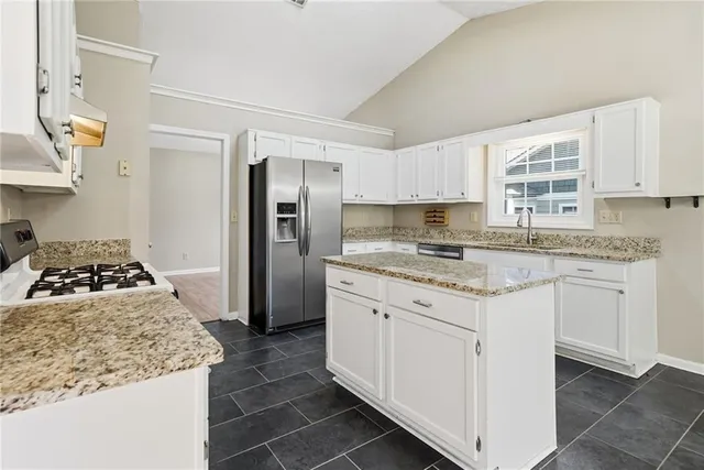 a kitchen with granite countertop a sink stove and refrigerator