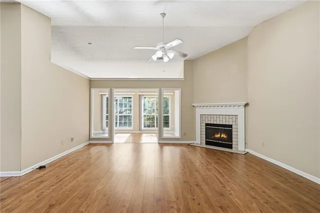 a view of an empty room with wooden floor fireplace and a window