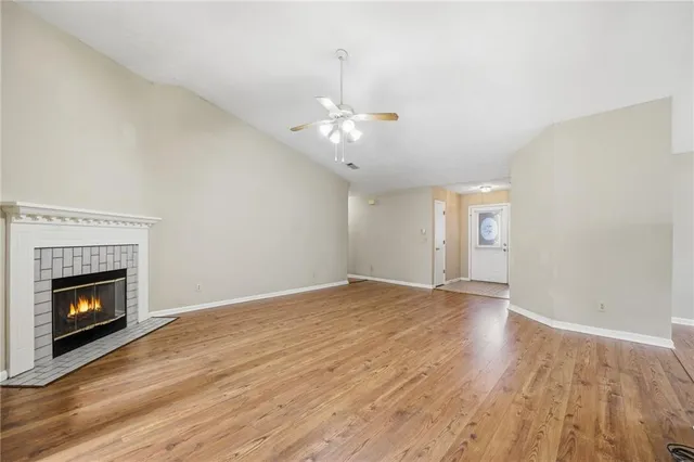 a view of an empty room with wooden floor fireplace and a window
