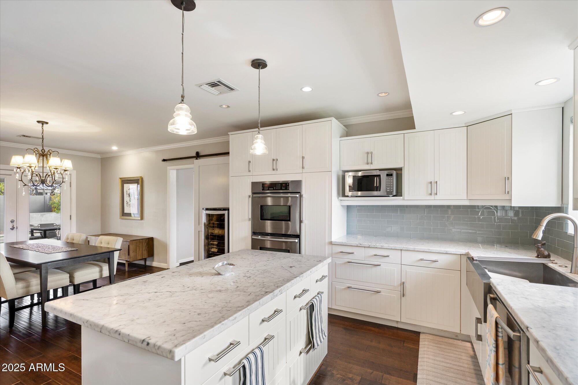 3328 East Turney Avenue Phoenix, AZ 85018 - Photo 9 of 35 a kitchen with a stove a sink a kitchen island with chairs and white cabinets
