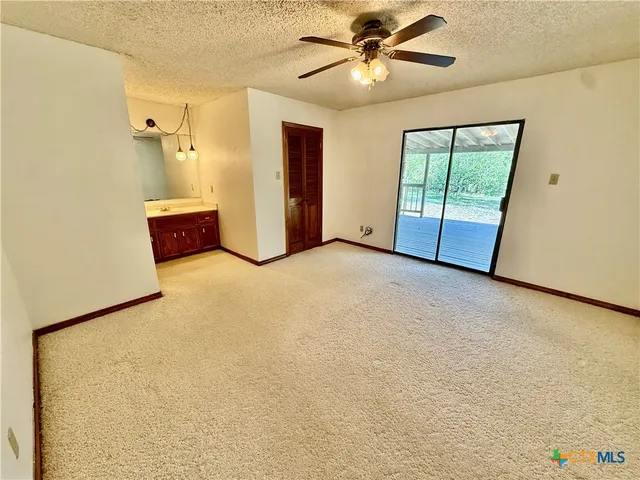 an empty room with chandelier fan and windows