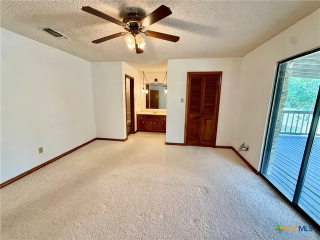 an empty room with closet and a ceiling fan