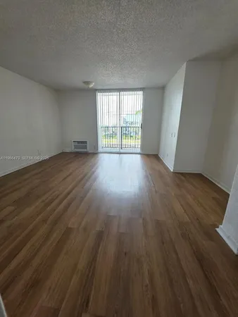 a view of an empty room with wooden floor and glass door