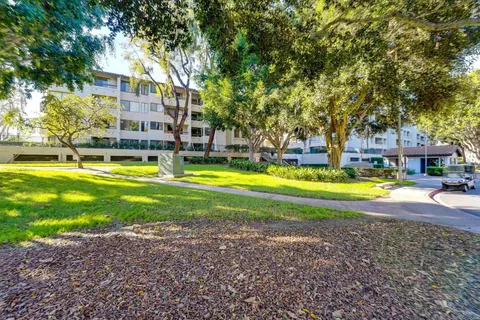 a view of a swimming pool with lawn chairs and large trees