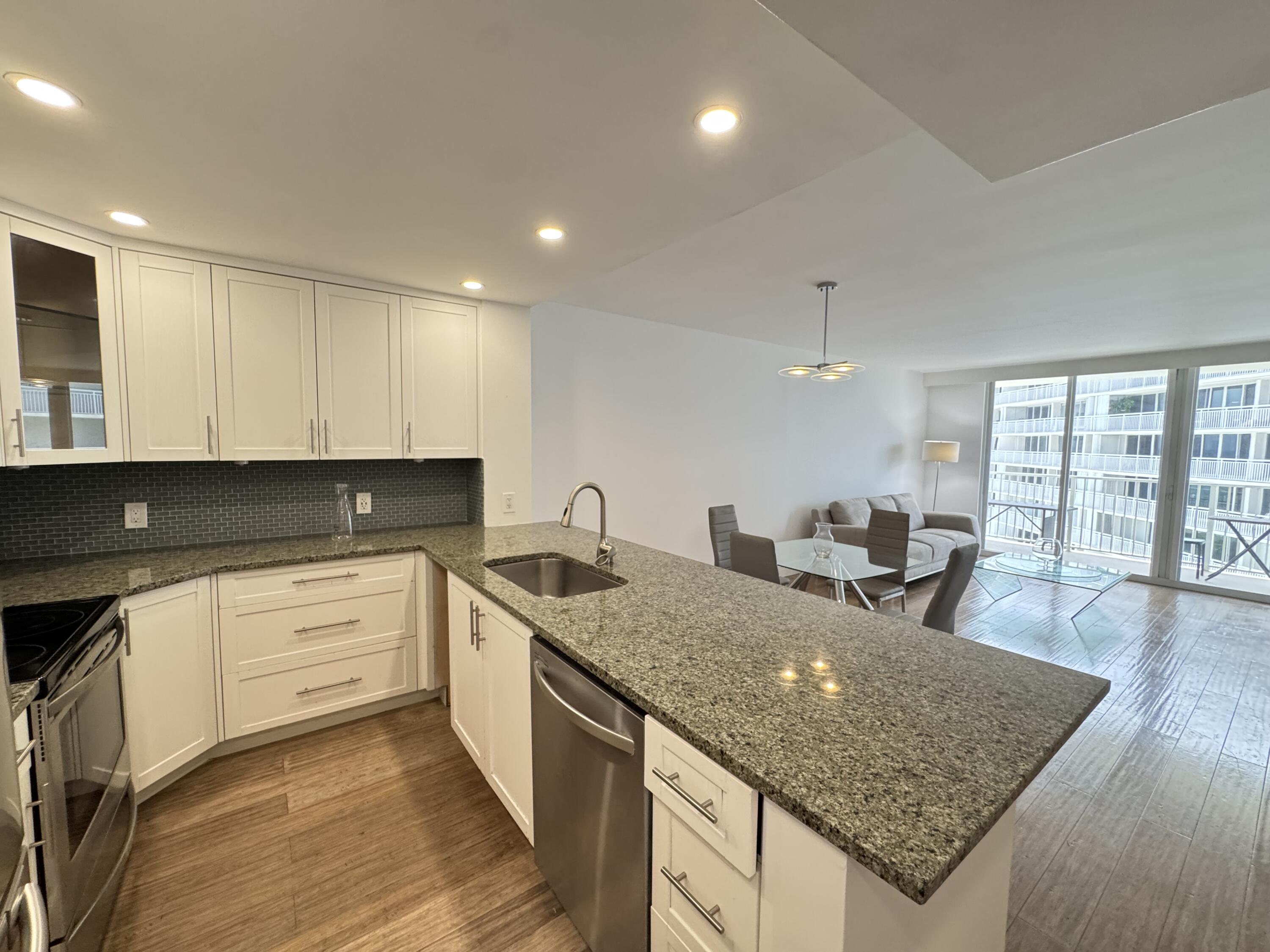 3540 South Ocean Boulevard, Unit 608 South Palm Beach, FL 33480 - Photo 5 of 35 a kitchen with stainless steel appliances granite countertop a sink dishwasher and stove with wooden floor