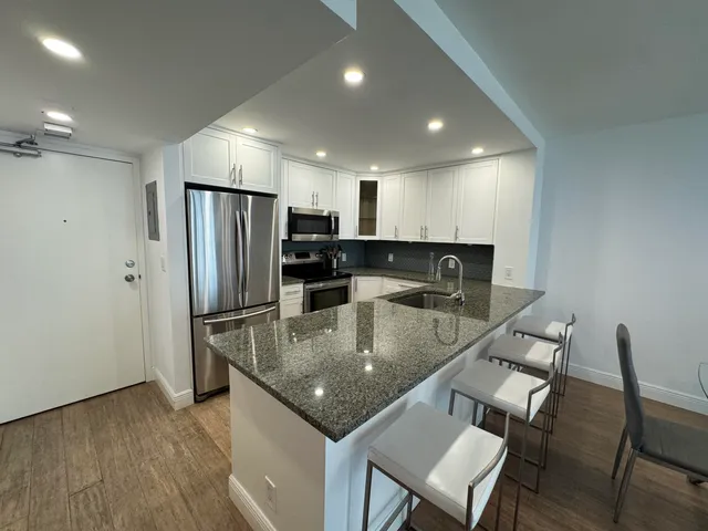 a kitchen with stainless steel appliances granite countertop a sink refrigerator and chairs
