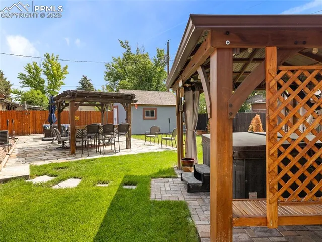 a view of a backyard with table and chairs potted plants and a palm tree