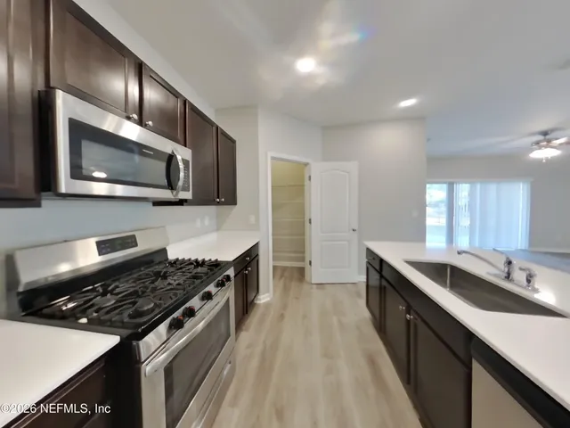 a kitchen with stainless steel appliances granite countertop a stove a sink and a microwave