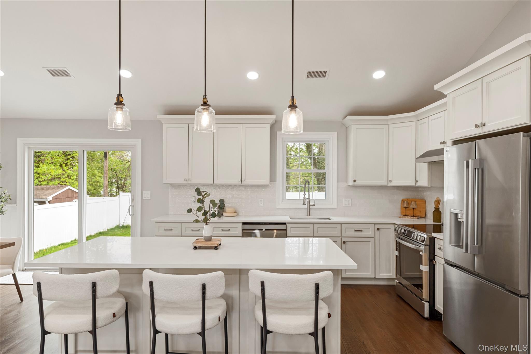 16 Eleanor Road Plainview, NY 11803 - Photo 7 of 28 Modern kitchen featuring a center island, white shaker-style cabinetry, stainless steel appliances, and wood floors