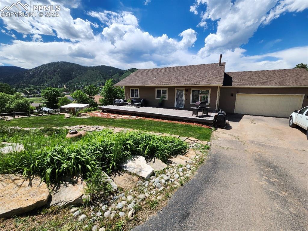 Single story home featuring driveway, a deck with mountain view, and a garage