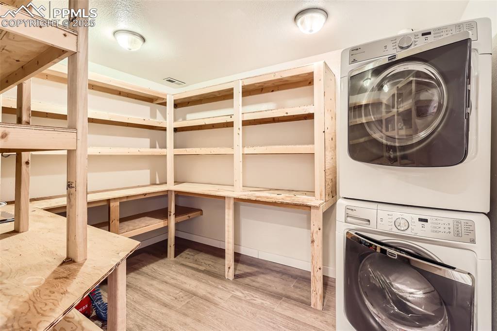 151 Star View Circle Palmer Lake, CO 80133 - Photo 27 of 36 Laundry room with stacked washer and clothes dryer, light wood finished floors, and baseboards