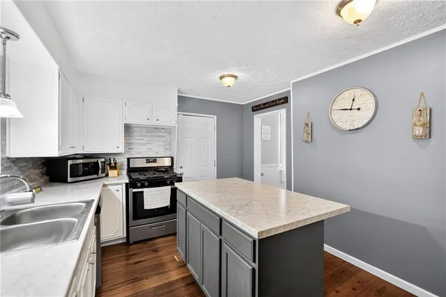 a kitchen with a stove a sink dishwasher a refrigerator with white cabinets and wooden floor