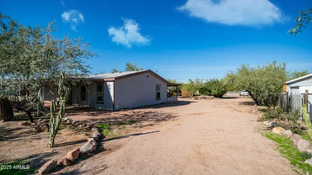 a backyard of a house with table and chairs and a large tree