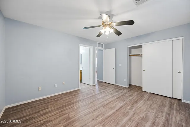 an empty room with wooden floor fan and windows