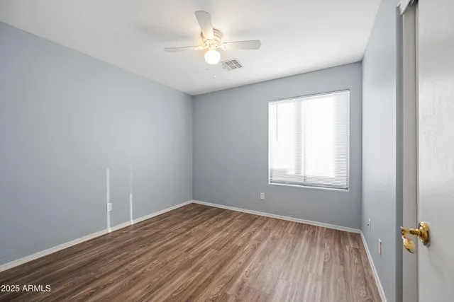 an empty room with a window and a ceiling fan