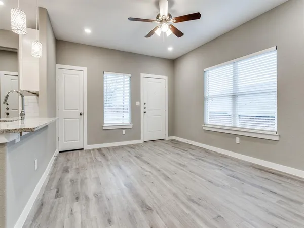 a view of empty room with wooden floor and fan