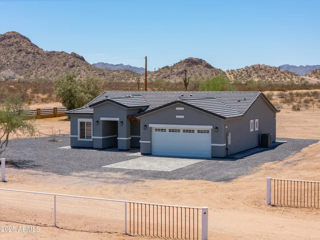 a front view of a house with a yard and mountain view in back