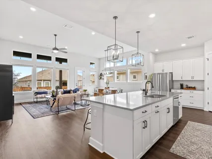 a kitchen with stainless steel appliances granite countertop a stove a sink a oven a dining table and chairs with wooden floor