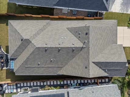 an aerial view of a house with swimming pool and large trees