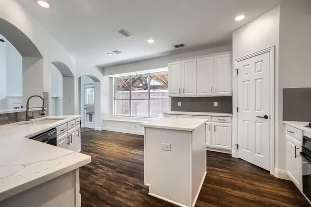 a kitchen with granite countertop a sink stove and cabinets