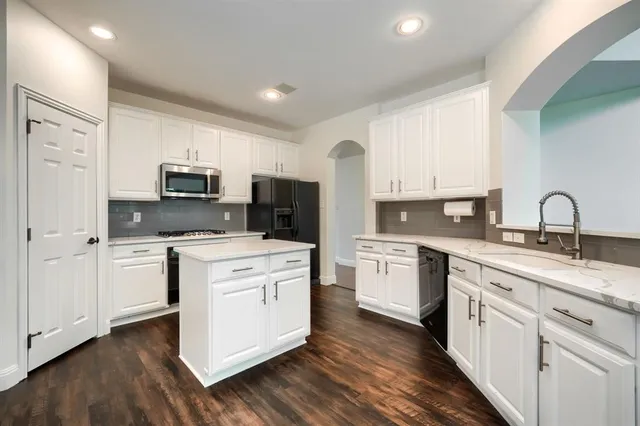 a kitchen with white cabinets stainless steel appliances and sink
