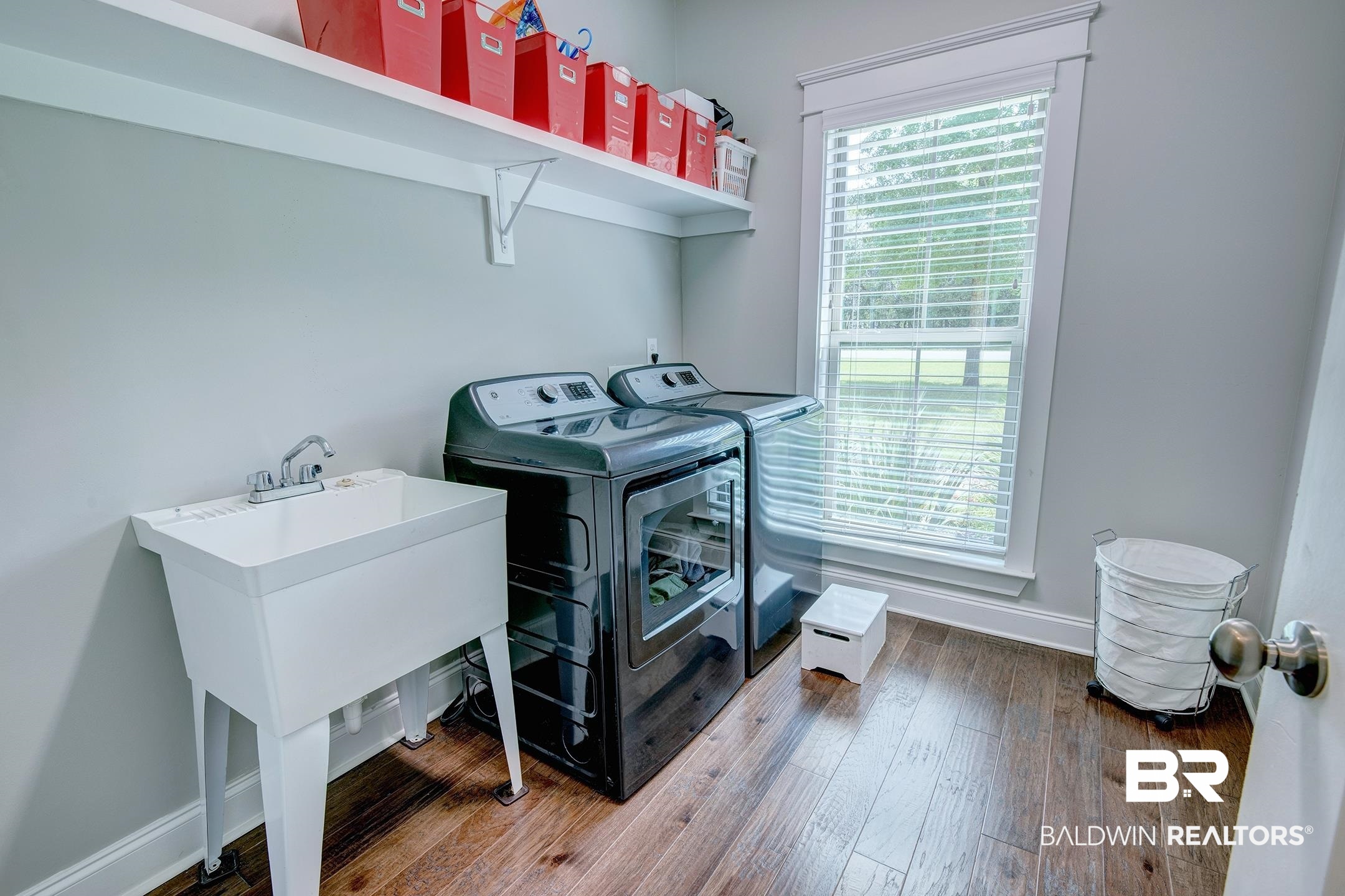 18754 Treasure Oaks Road Gulf Shores, AL 36542 - Photo 34 of 53 Dedicated laundry space featuring wood-finish flooring, a utility sink with a chrome faucet, and a large window with white trim