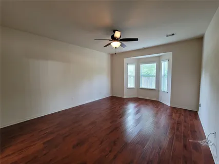 a view of an empty room with wooden floor and a window