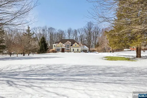 a view of white house with a yard and large trees